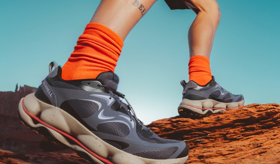 Close-up of Merrell SpeedARC shoes with orange socks on red rock